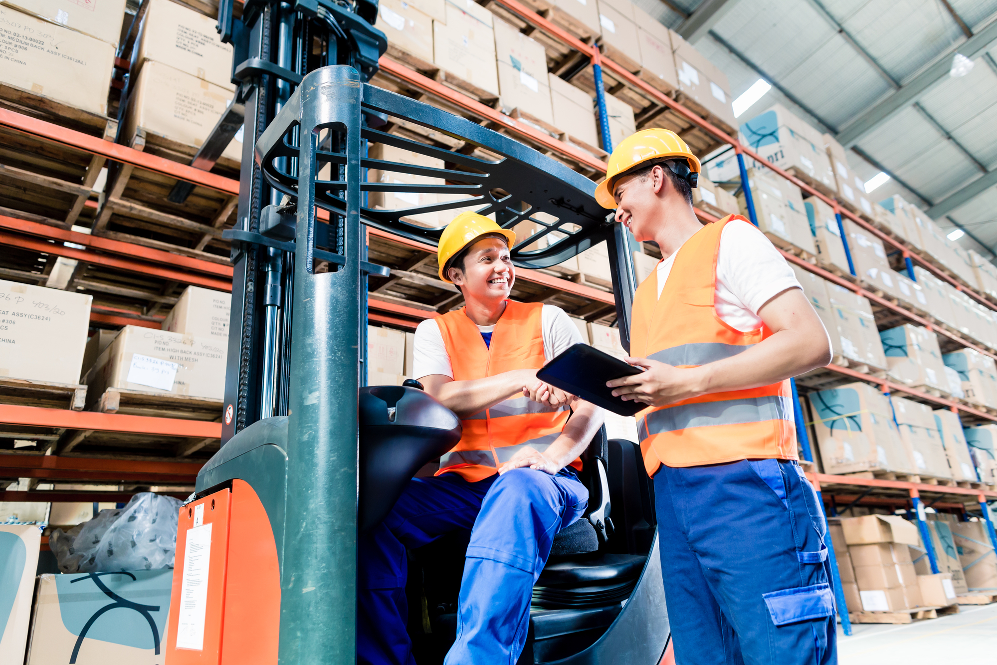Workers in logistics warehouse at forklift checking list